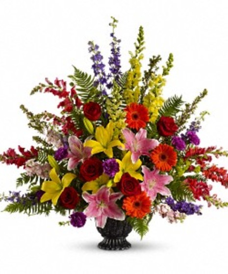 Sympathy urn filled with seasonal flowers in bright colors. 