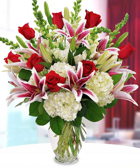 Bouquet of red roses, stargazer lilies, white snapdragons & white hydrangea in a glass vase. 